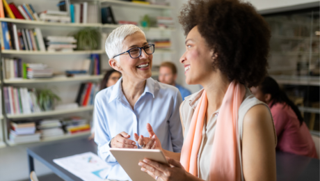 Two women in office talking and smiling